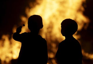 Two children watch a bonfire during the traditional San Juan's night in Paredes, northern Spain