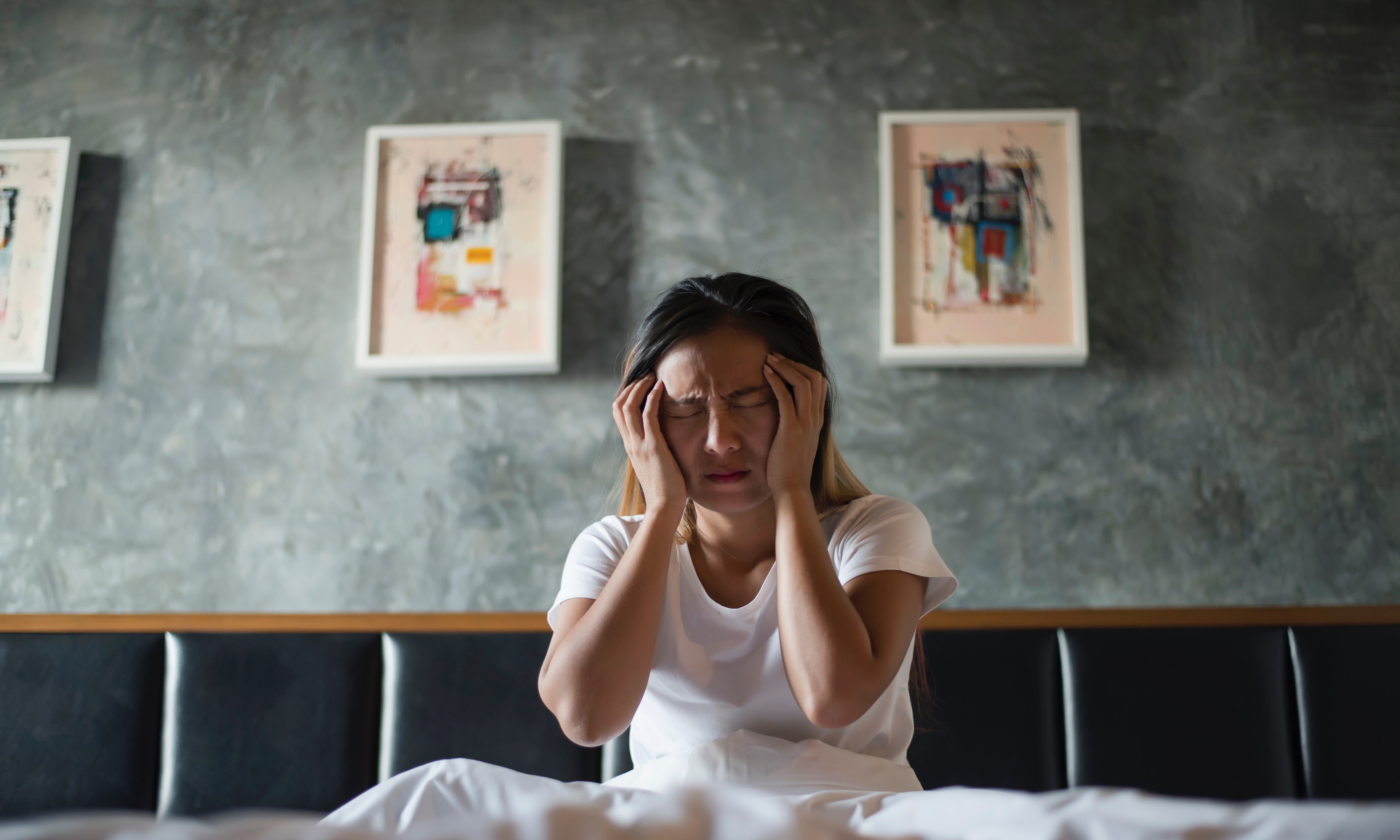 depressed-woman-with-headache-hand-holding-her-head-bed