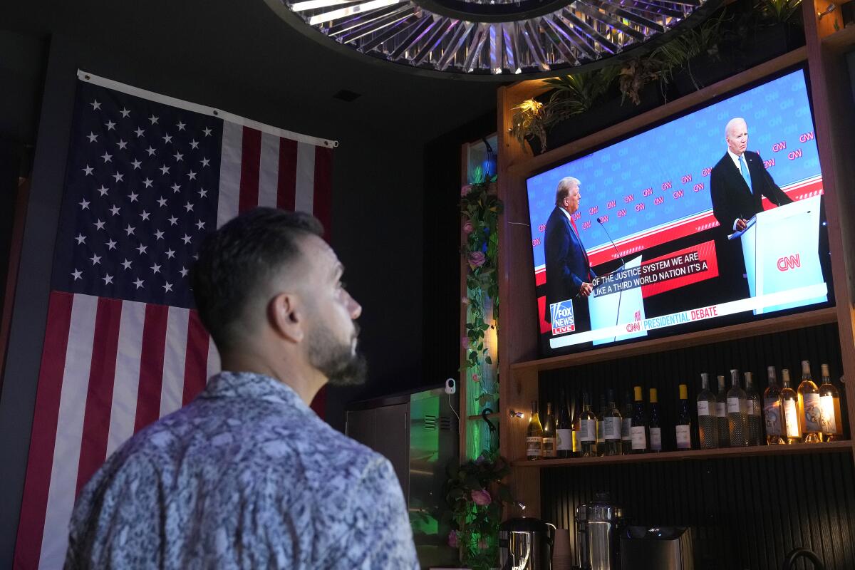 A man looks up at a TV screen showing the Trump-Biden debate