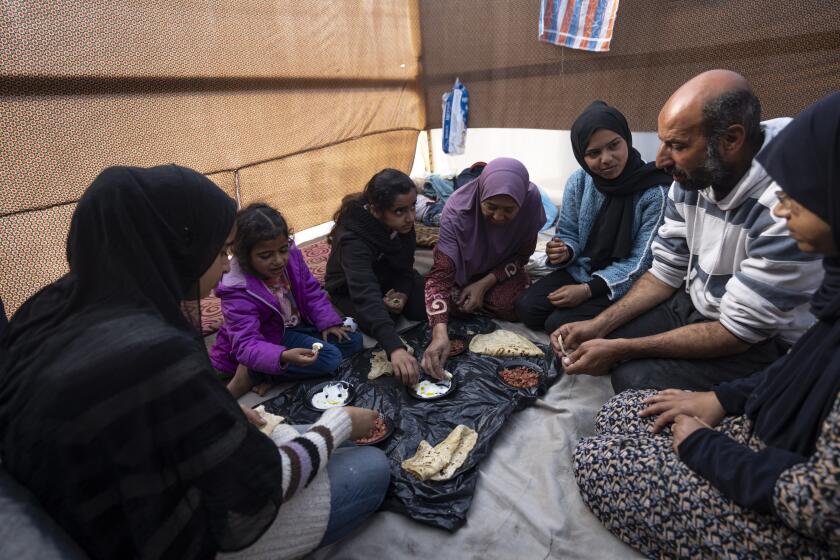 Members of the Abu Jarad family, who were displaced by the Israeli bombardment of the Gaza Strip, eat breakfast at a makeshift tent camp in the Muwasi area, southern Gaza, Monday, Jan. 1, 2024. (AP Photo/Fatima Shbair)