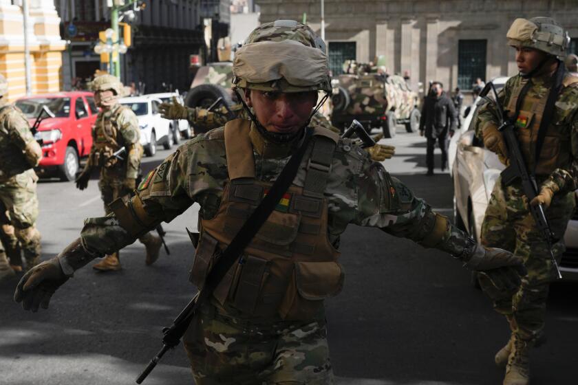 A soldier gestures for journalists to leave Plaza Murillo as soldiers gather near the presidential palace in Plaza Murillo in La Paz, Bolivia, Wednesday, June 26, 2024. (AP Photo/Juan Karita)