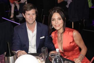Paul Bernon and Bethenny Frankel in formalwear smile while seated at a dining table