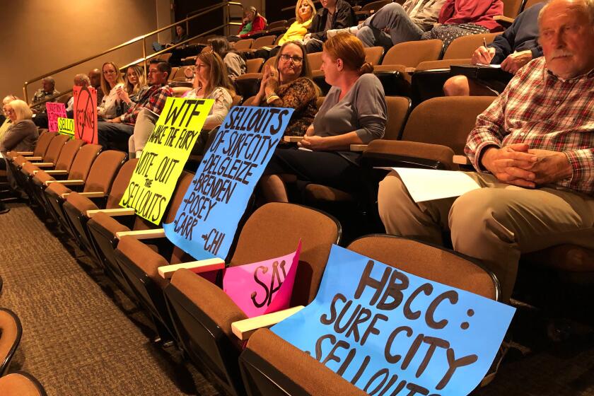 Signed held by protesters in the audience at Monday's Huntington Beach City Council meeting showed strong opposition to the Magnolia Tank Farm Specific Plan redevelopment process and called council members "sell outs" for their appointed planning commissioners who approved the project's latest resolutions.