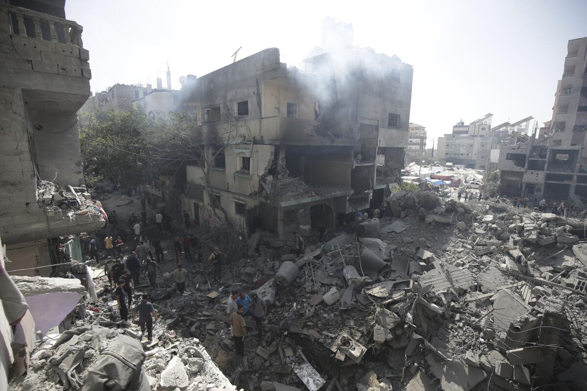 Palestinians look at the aftermath of the Israeli bombing in Nuseirat refugee camp.