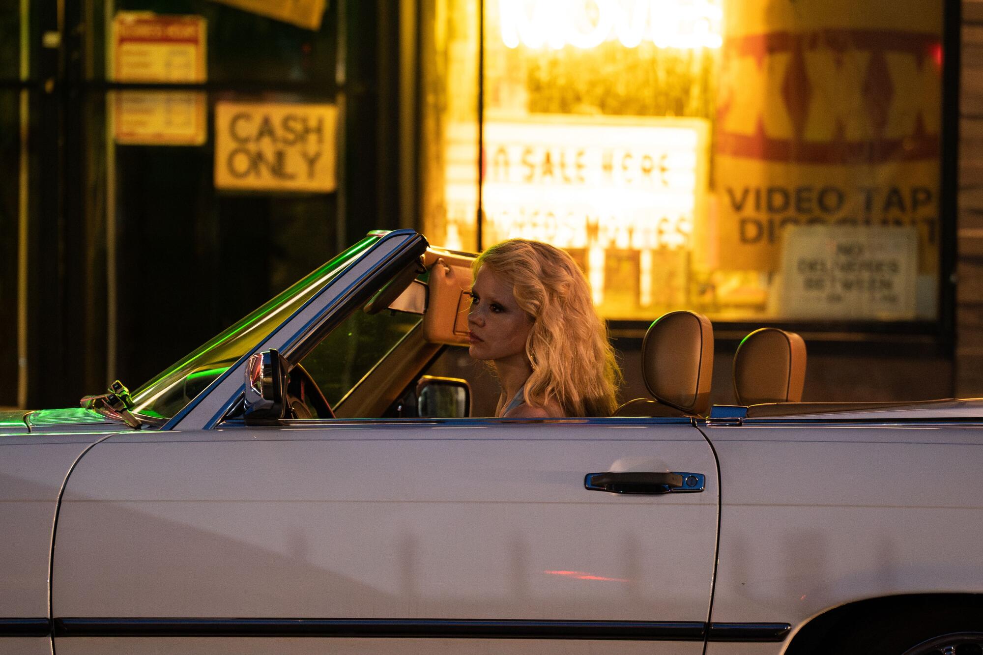 A woman sits in her car outside a video store in Hollywood.