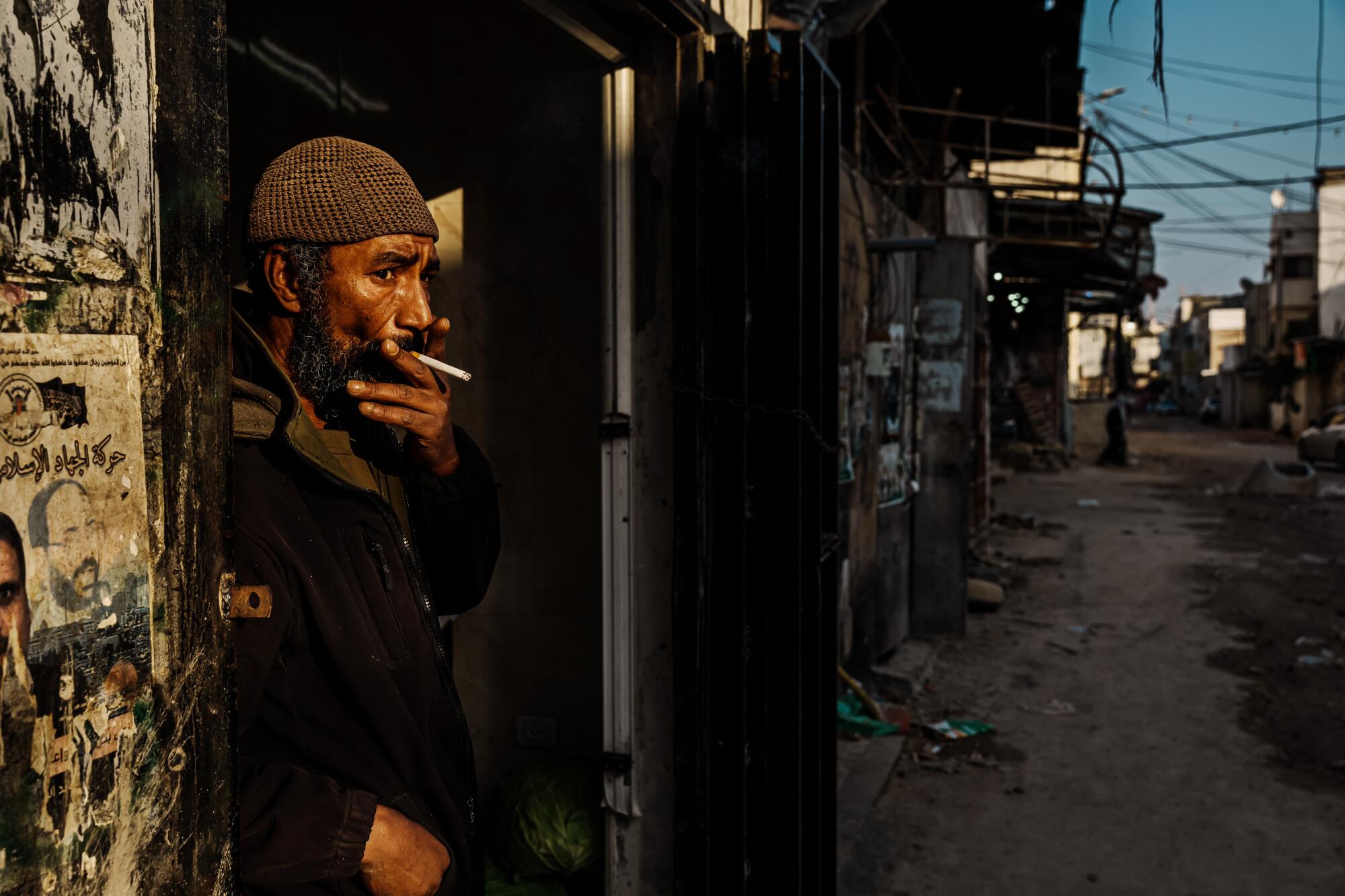Abu Muhammad smokes a cigarette and looks at the damaged main road that goes through Jenin.