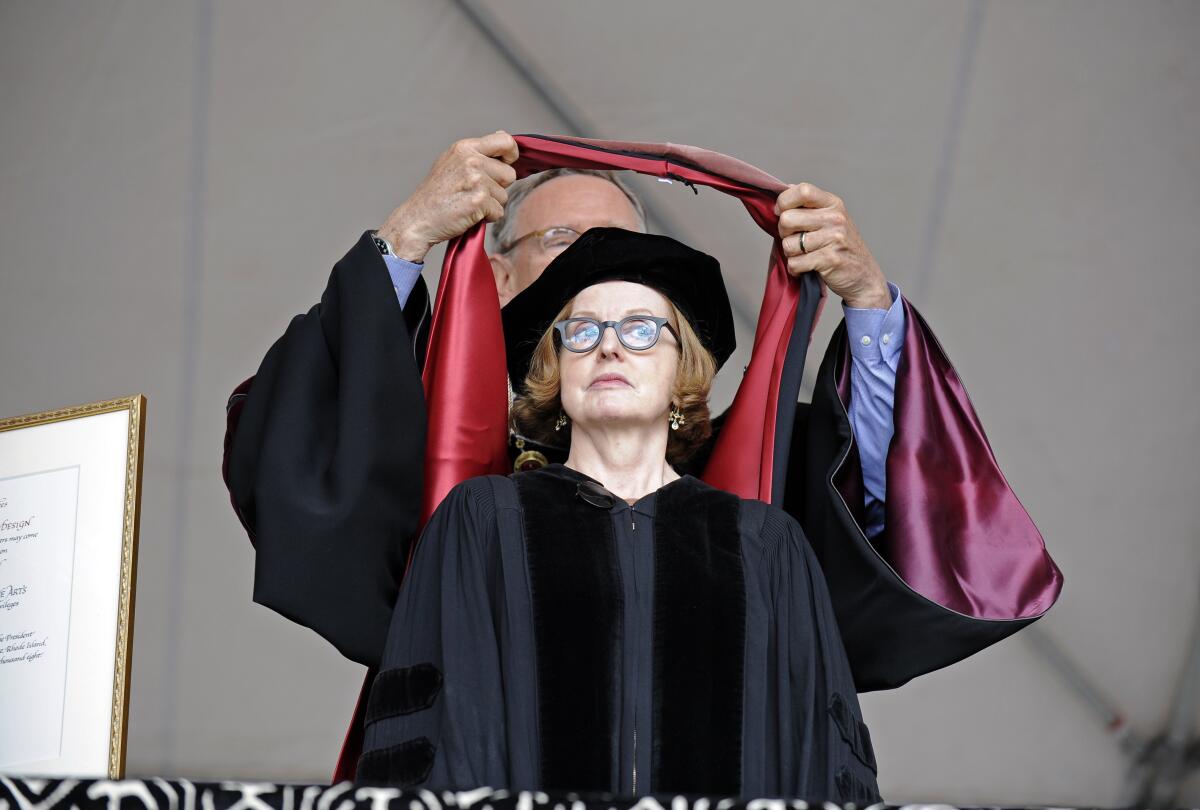Roberta Smith has ceremonial ribbons placed over her head during a graduation ceremony.