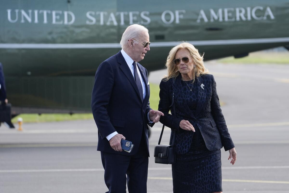 President Biden and First Lady Jill Biden talk on an airport tarmac in front of an aircraft marked "United States of America"