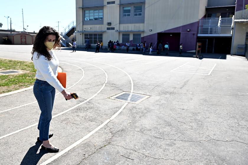 Robin Mark, of the Trust for Public Land, measures the surface temperature of the asphalt at Castellanos Elementary in L.A.