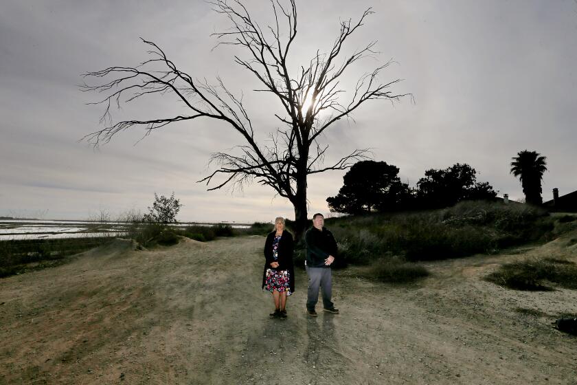 Two people stand on coastal land that Orange County has returned to indigenous tribes 