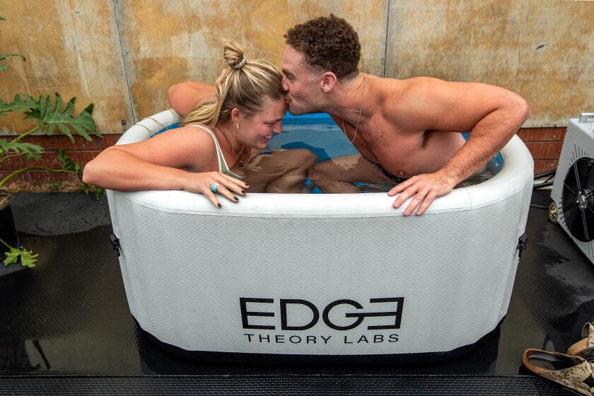 VENICE, CA-SEPTEMBER 16, 2023: Emma Soave, 27, of Venice, gets a kiss from Julian Rothschild, 25, of Los Angeles, while preparing to exit an ice bath with the temperature set to 38 degrees during a singles mixer in Venice where eligible singles participated in cold plunge speed dating. (Mel Melcon / Los Angeles Times)