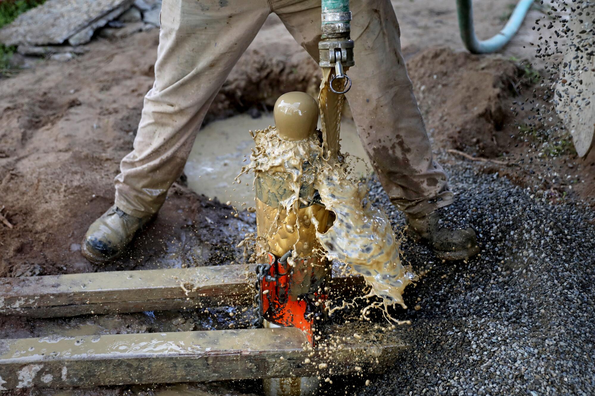 A worker places gravel around a newly drilled well.