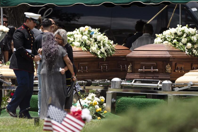 Two women comfort each other during the burial service for Irma Garcia and her husband Joe Garcia at Hillcrest Cemetery, Wednesday, June 1, 2022, in Uvalde, Texas. Irma Garcia was killed in last week's elementary school shooting. Joe Garcia died two days later. (AP Photo/Jae C. Hong)