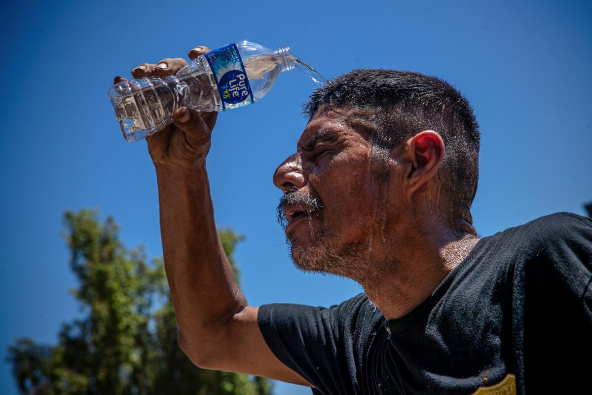 A man pours water from a bottle onto his head.