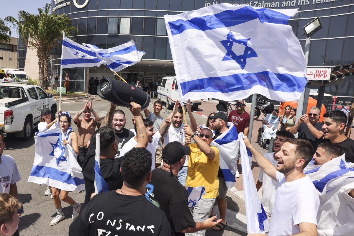People wave Israeli flags as they celebrate after hostages were rescued.