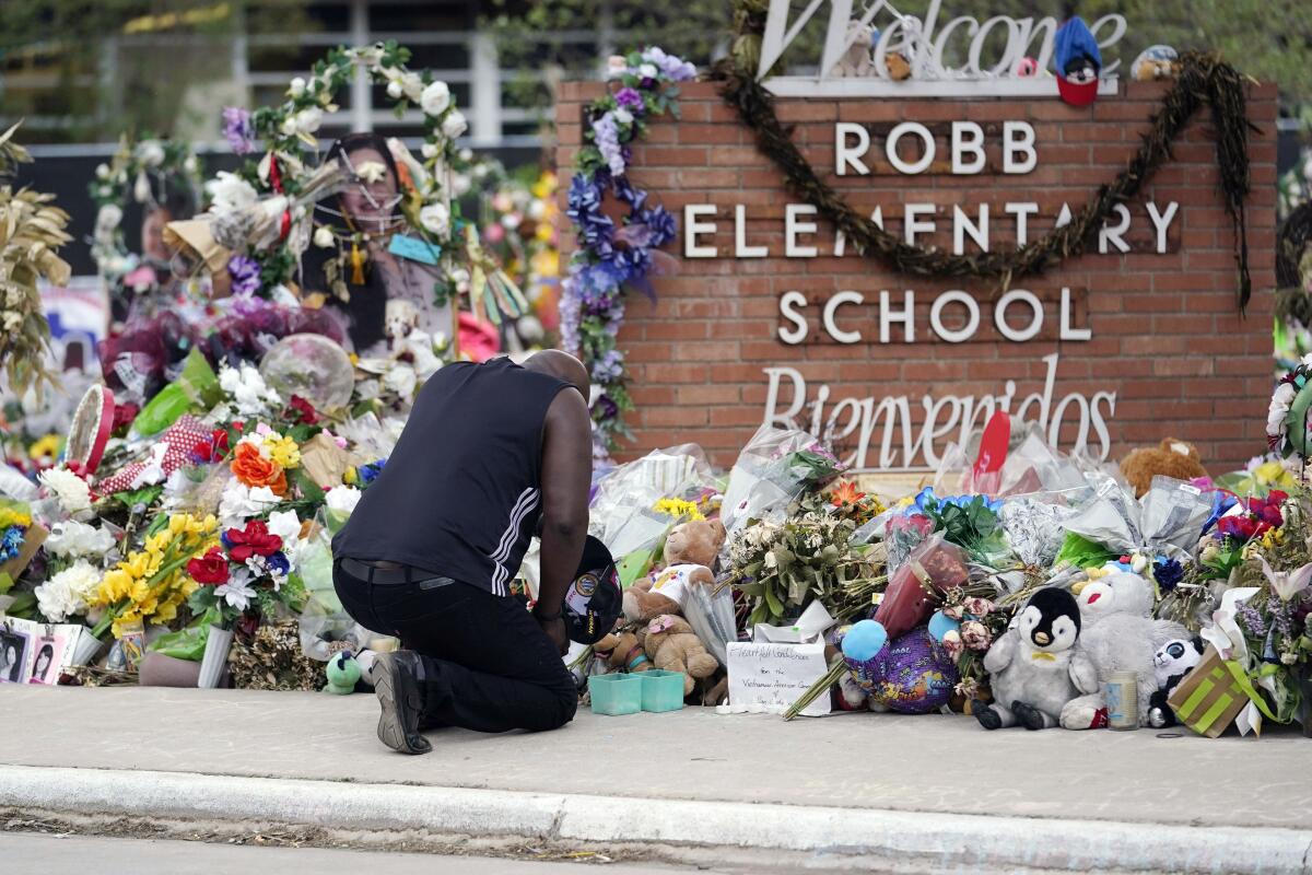 A person kneels at a memorial at Robb Elementary School in Uvalde, Texas.