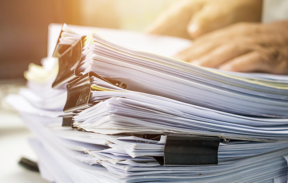 Businessman hands searching data information in Stack of papers