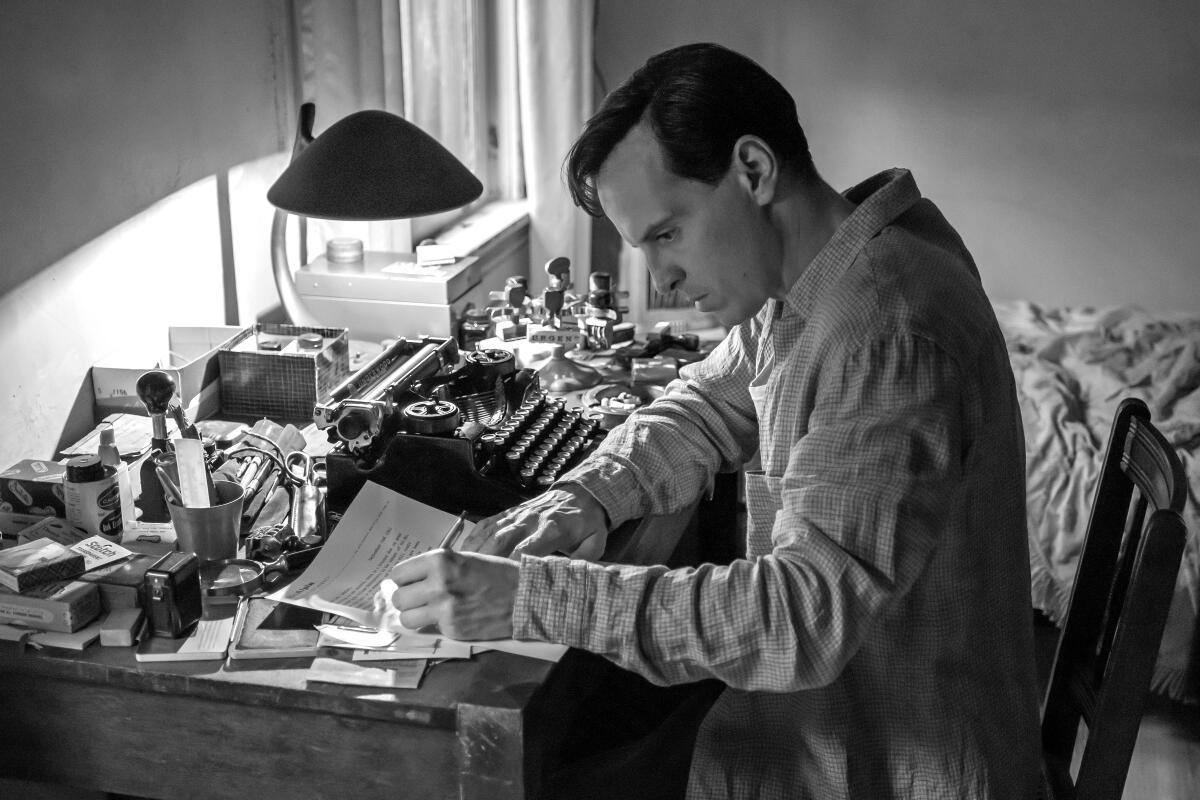 A man sits in a cramped and messy room writing on paper next to a typewriter in "Ripley."