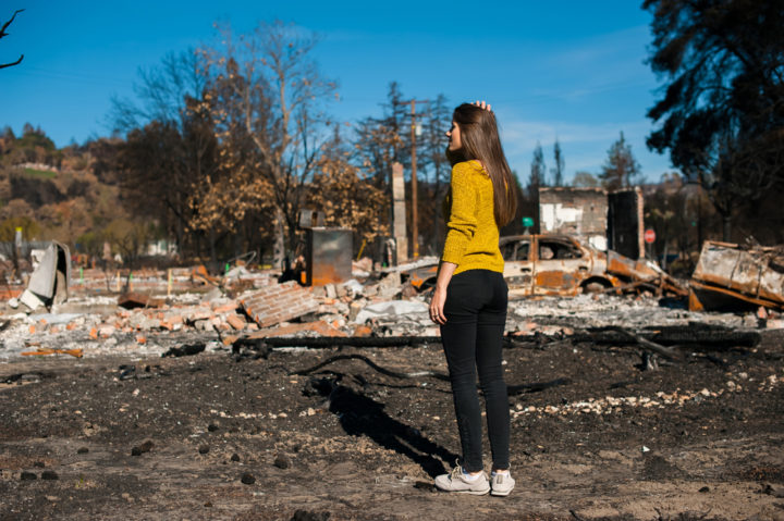 Woman looking at wildfire destroyed house