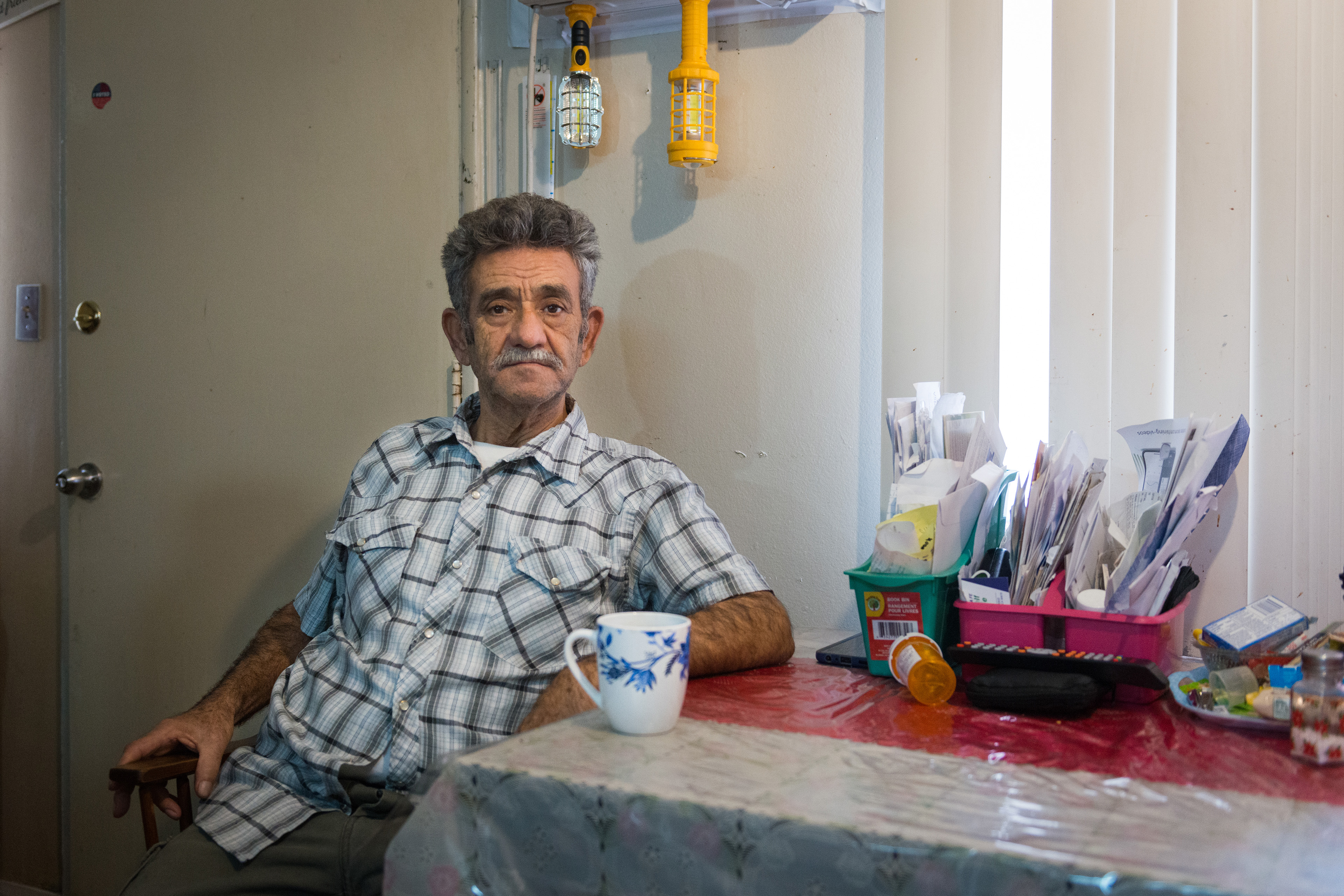 Lucas Moreno Ramirez sits at his kitchen table and looks directly at the camera. His medication is visible beside him.