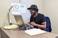 A photo of a man working on a laptop indoors.