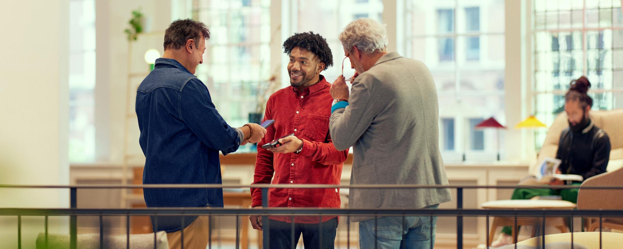 Two individuals exchanging a smartphone during a friendly interaction indoors.