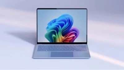 Open Microsoft laptop with the rainbow bloom on the screen on a light blue gradient background