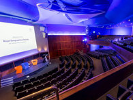 View from the balcony in the Ondaatje Theatre at the Royal Geographical Society. A presentation slide is projected on the screen and says 'Welcome to the Roayl Geographical Society'.