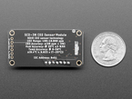 Back view of a Adafruit SCD-30 - NDIR CO2 Temperature and Humidity Sensor next to US quarter for scale. 