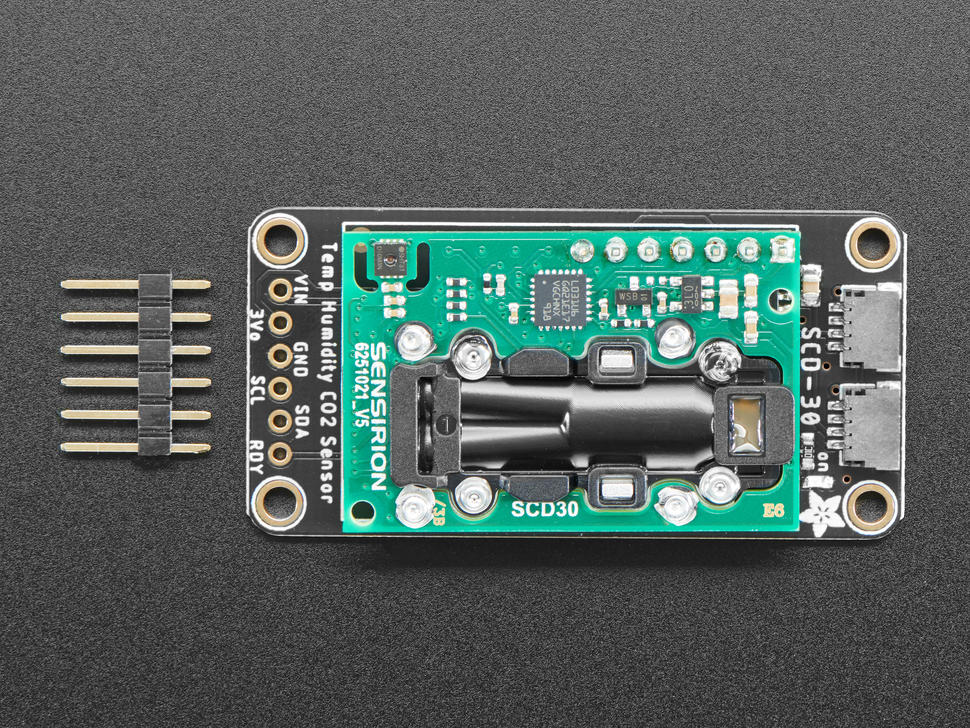 Adafruit SCD-30 - NDIR CO2 Temperature and Humidity Sensor next to a 6-pin header. 