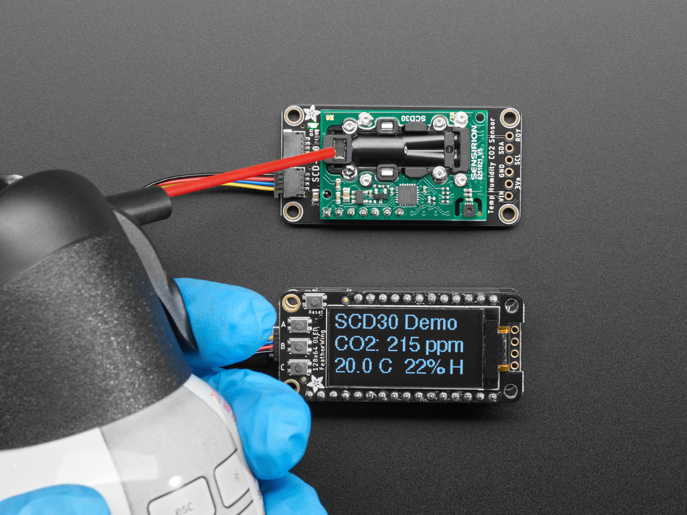 Still image of someone blowing a dust on a Adafruit SCD-30 - NDIR CO2 Temperature and Humidity Sensor. 