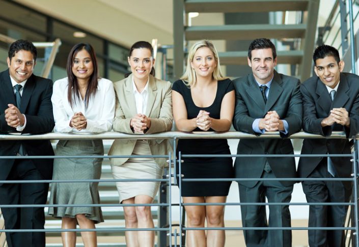 Men and women with hands clasped together, standing along a guard rail.