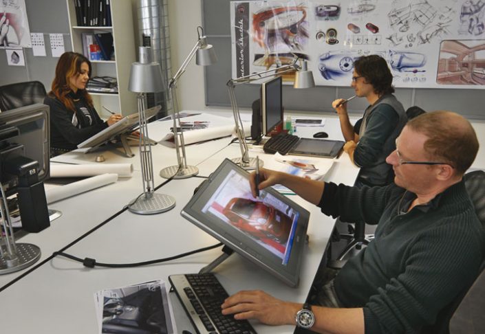 Employees seated around a large table working on computers.