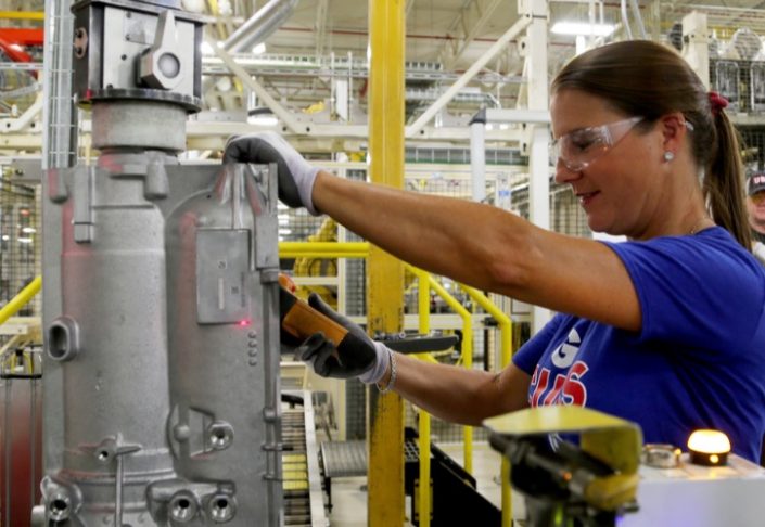 Woman wearing safety goggles working in a manufacturing facility.