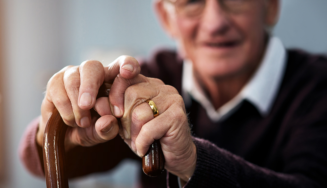 A blurred close up of a man holding a cane