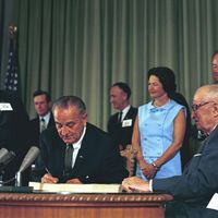 President Lyndon B. Johnson signing the Medicare Bill at the Harry S. Truman Library in Independence, Missouri. Former President Harry S. Truman is seated at the table with President Johnson.