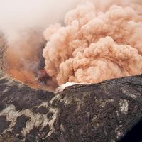 Ash cloud rising from the Kilauea Volcano Pu`u `O `o as crater floor collapses due to magma withdrawal. Incandescent rubble can be seen crumbling and rolling down the scarp. East rim of Pu`u `O `o is in the foreground, Kilauea, Hawaii on March 6, 2011.