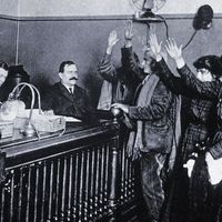 Black and white photo of people in courtroom, hands raised, pledging