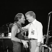 President Jimmy Carter greets Willie Nelson on stage after watching the country and western music singer perform in a concert at the Merriweather Post Pavilion in Columbia, Maryland on July 21, 1978.