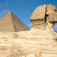 Al-Jizah. Giza Necropolis, Giza Plateau, Cairo, Egypt. Side view of Sphinx with the Great Pyramid of Khufu (Cheops) rising in the background. The sides of all three of the Giza pyramids are astronomically oriented to be north-south, east-west (see notes)