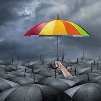 Umbrella colored like a rainbow sticking out above a sea of black umbrellas while it rains. (storm, weather)