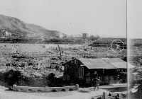 １９４５年８月２０～２４日に、浦上天主堂付近から南方向を藤田哲也氏が撮影した写真。手前のバラックの後方に別のバラック（円部分）が小さく写っている＝長崎原爆資料館所蔵