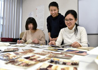 原爆資料館の土肥幸美学芸員（中央）とともに作業する宮迫陽奈さん（左）と小糸咲月さん＝広島市中区で、山田尚弘撮影