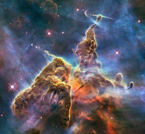 Hubble's 20th anniversary image shows a mountain of dust and gas rising in the Carina Nebula. The top of a three-light-year tall pillar of cool hydrogen is being worn away by the radiation of nearby stars, while stars within the pillar unleash jets of gas that stream from the peaks.(c)NASA