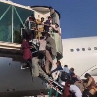 アフガニスタンの首都カブールの空港とみられるツイッターへの投稿画像。旅客機の入り口に多くの人が殺到している＝ツイッターの動画より