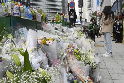 火災現場の雑居ビル前に手向けられた花束に手を合わせる女性＝大阪市北区で２０２１年１２月２２日午後３時５７分、藤井達也撮影