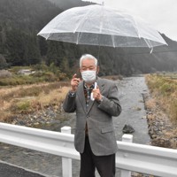 黒い雨の援護対象区域を分ける境界線となった川にかかる橋に立ち、「線引きのおかしさを突くところから運動は始まった」と話す武田知明さん＝広島市佐伯区湯来町で2022年3月23日午後2時55分、小山美砂撮影