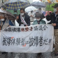 雨の中、被爆者健康手帳の交付を求める訴訟のため長崎地裁に入る被爆体験者たち＝長崎市で2022年4月26日午後3時58分、樋口岳大撮影