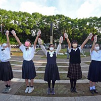 原爆落下中心地碑の周りを「人間の鎖」でつなぎ、平和を祈る高校生たち＝長崎市の爆心地公園で2022年8月9日午前7時17分、徳野仁子撮影