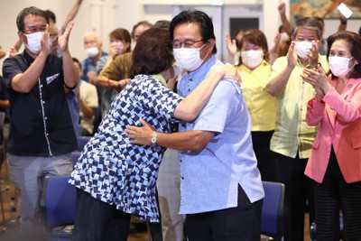 参院選沖縄選挙区で再選が確実となり、妻と抱き合う「オール沖縄」勢力の現職、伊波洋一氏（中央）＝那覇市で2022年7月11日午前0時、喜屋武真之介撮影